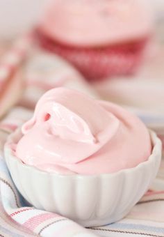 two cupcakes with pink frosting in them on a striped table cloth next to each other