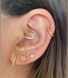 a woman wearing three different ear piercings with the word's written on them