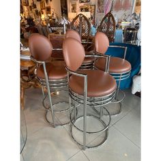 four brown leather stools are stacked on top of each other in front of a table