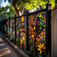 a fence made out of stained glass with trees and flowers painted on the side it