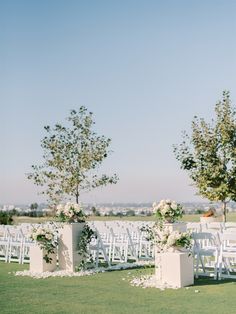 an outdoor ceremony setup with white chairs and flowers