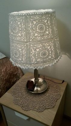 a lamp that is sitting on top of a night stand next to a nightstand with a drawer