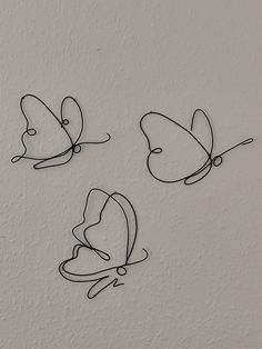 three metal butterflies sitting on top of a white wall