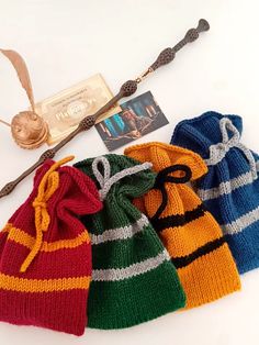 three knitted harry potter beanies are lined up next to each other, one with a wand in it