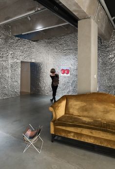 a woman is standing in an empty room with a couch and chair next to it