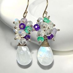 Rainbow Moonstone Cluster Earrings, Multi Gemstone Dangle Earring, Green Purple Gem Drop Earring, Oxidized Silver Earrings, Gift for Mom, Blue Flash Moonstone Earrings, Amethyst, Green Topaz Earrings Indulge in the romance of late summer with these purple, green and rainbow moonstone cluster earrings.  These alluring earrings whisper the charm of purple, green and lightly oxidized sterling silver together over shimmering blue and rainbow flashes from the rainbow moonstone briolettes.  These are a perfect match for your cozy blue, grey, green and plum sweaters and complementary evening attire.  Watch your admirers be captivated! ~ ~ Faceted, extremely flashy rainbow moonstone briolettes dangle from (lightly oxidized) sterling silver handmade ear wires with clusters of strong blue flash rain White Teardrop Gemstone Crystal Earrings, White Teardrop Crystal Earrings With Gemstone, Handmade White Dangle Cluster Earrings, Teardrop Moonstone Earrings With Gemstone Accents, White Gemstone Crystal Dangle Earrings, White Gemstone Dangle Crystal Earrings, White Gemstone Accented Round Earrings, White Dangle Jewelry With Gemstone Accents, White Dangle Earrings With Natural Stones