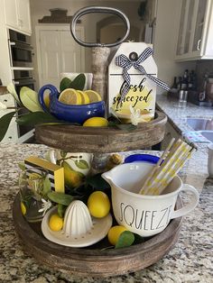 a three tiered tray with lemons and tea cups on it in a kitchen