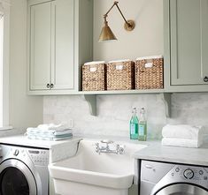 a washer and dryer in a small room with green cabinets, white marble counter tops