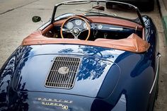 an old blue sports car parked on the side of the road