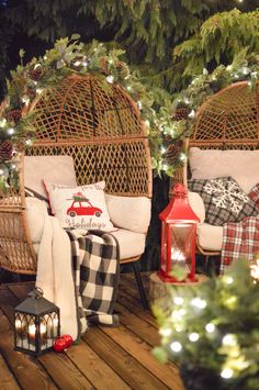 two wicker chairs sitting on top of a wooden deck next to a christmas tree