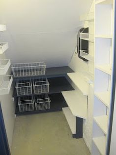 an empty room with shelves and bins on the floor in front of a microwave