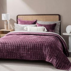 a bed with purple bedspread and white pillows