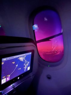 the view from inside an airplane looking out at the sky and clouds with purple lights