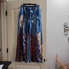 a pair of blue jeans hanging on a door with an open front pocket and multicolored patchwork design