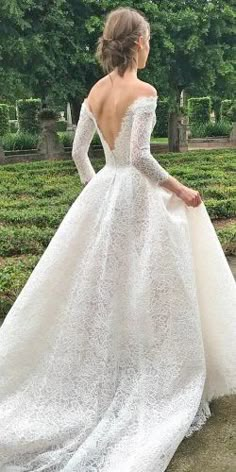 a woman in a white wedding dress is standing on the ground with her back to the camera