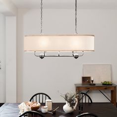 a dining room table with four chairs and a light fixture hanging from it's ceiling