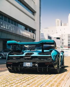 a blue and black sports car parked on the side of a road in front of a building