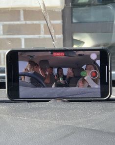 a cell phone sitting on top of a car dashboard with people in the back seat