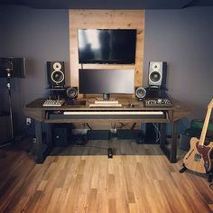 a desk with speakers, guitar and monitor on it