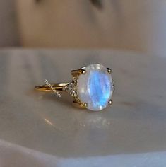 "Most Welcome to \"TheJewelryArts\" Products Description Center Stone: Genuine Rainbow Moonstone Center Stone Size: 10x12mm Stone Shape: Oval Cut Side Stone: Cubic Zircon Stone Clarity: VVS Material: 92.5 Sterling Silver, also available in 24k Rose Gold Vermeil/Gold Vermeil/Black Vermeil Stamp: 92.5 ➽OCCASION: Surprise your loved one with this beautiful engagement/wedding jewelry by TheJewelryArts . A classic piece of jewelry for all men/women in your life, this is a perfect gift for any occasion such as birthdays, anniversaries, wedding, engagements, Valentine's Day or Christmas day mother's day. ✔Comfort Fit ✔Nickel Free ✔Free Engraving ✔ Free Shipping ✔  Ready to Ship in 3 Business Day Customization is always welcome and please feel free to contact with me if you have any design ideas! Gold Moonstone Crystal Ring, Gold Moonstone Ring As Gift, Gold Moonstone Ring For Gift, Gift Yellow Gold Moonstone Ring With Accent Stones, Gold Moon Shaped Moonstone Ring Gift, Gold Moon-shaped Moonstone Ring Gift, Gold Moonstone Ring Shaped Like Moon For Gift, Gold Moonstone Ring With Accent Stones, Gift Moonstone Ring With Round Accent Stones