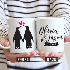 two coffee mugs with penguins on them, one has a heart and the other has a penguin