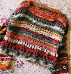 a crocheted sweater laying on top of a bed