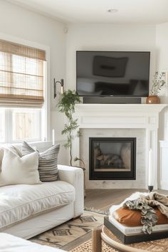 a living room with white furniture and a flat screen tv on the fireplace mantel