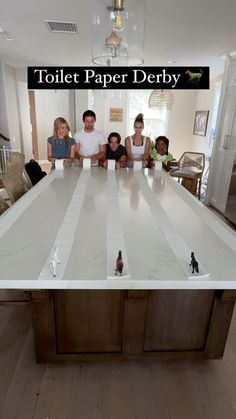 a group of people sitting at a table with paper on it that says toilet paper derby