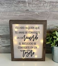 a wooden frame with the words in spanish on it next to a potted plant