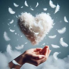 a heart shaped cloud floating in the air with two hands holding it out to each other