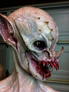 an alien head with large teeth and blood on it's face is shown in front of a door