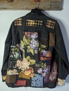 a jacket is hanging on a wall with flowers and other things attached to the back