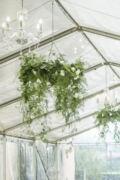 an indoor tent with flowers hanging from the ceiling and chandelier in the background