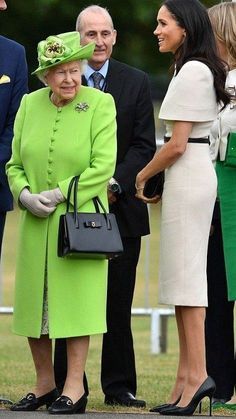 the queen and prince are standing next to each other in front of some people wearing green outfits