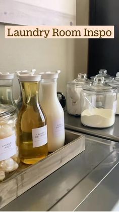 several bottles of liquid sitting on top of a metal shelf next to jars and containers