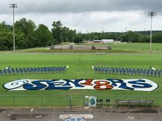 an empty field with chairs and a large banner on the grass in front of it