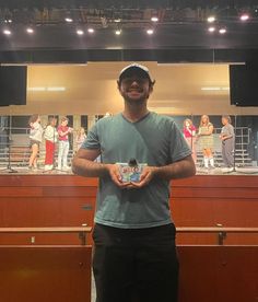 a man standing in front of a stage holding a small item with people on it