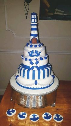 a large blue and white cake with cupcakes on the table next to it