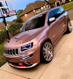 a pink jeep parked in front of a basketball hoop on the side of a house