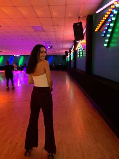 a woman standing on top of a wooden floor next to a bowling ball roller blade