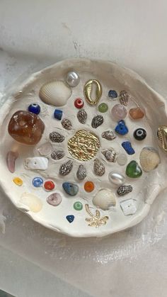 a white bowl filled with lots of different types of sea glass and seashells