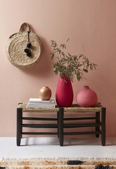 three vases are sitting on a bench in front of a pink wall