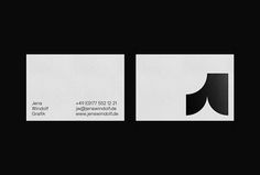 two black and white business cards sitting on top of each other in front of a dark background