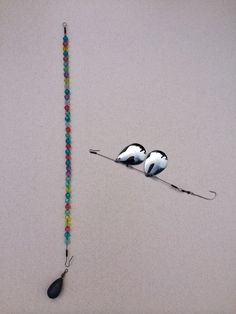 two birds on a long beaded necklace next to a hook with beads hanging from it