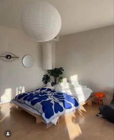 a bedroom with a large bed and white lamps hanging from it's ceiling above the bed