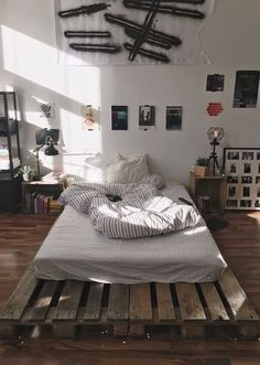 a bed made out of wooden pallets in a room with pictures on the wall