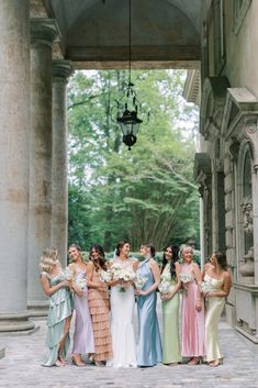 a group of women standing next to each other in front of a building with columns