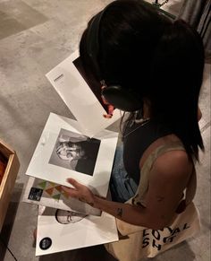 a woman sitting on the floor looking at pictures