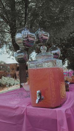 a pink table with disco balls hanging from it's sides and an ice bucket on top