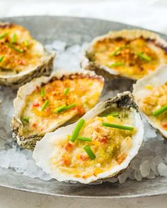 several oysters on ice with green onions and seasoning sprinkled around them